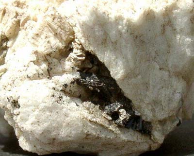 正長石のガマにできた鉄電気石の小さな結晶の写真